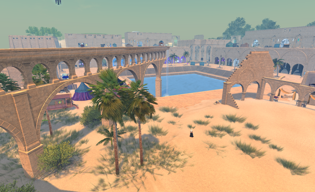 An aqueduct carries water from left to right and drains in a waterfall into a large square pool in the middle of a stone square. In the background long stone buildings with archways face the pool. Other, higher stone buildings stand behind those. In the foreground sand and desert grasses cover the paving. A partly ruined building stands off to the right.